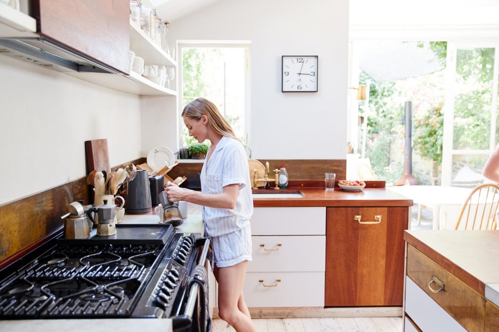 Woman Wearing Pajamas At Home In Kitchen Making Fresh Coffee